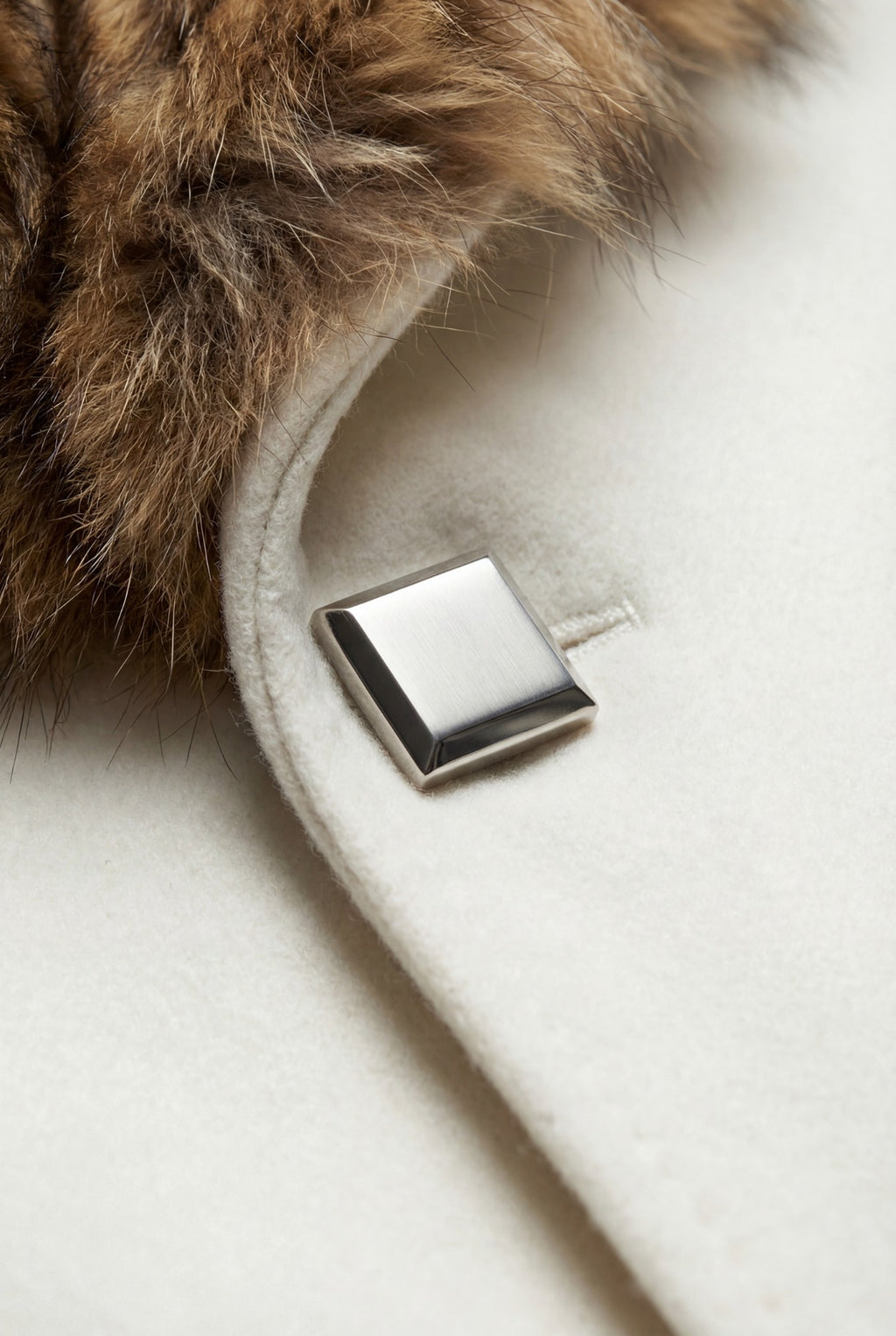 Ivory wool coat detail. Fox fur collar, square metallic closure, luxe outerwear.